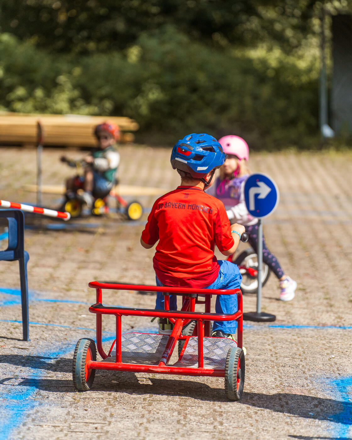 Kinder mit Helm fahren Rennen auf Tretfahrzeugen